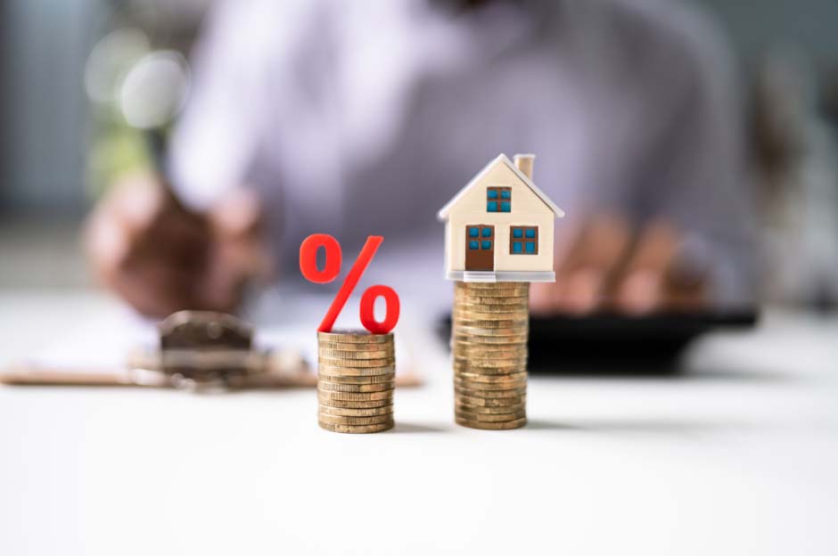 Photograph of stacks of pound coins one has a percentage sign on top and the other has a house, to symbolise mortgage rate switches offered by Whitewood Mortgages.